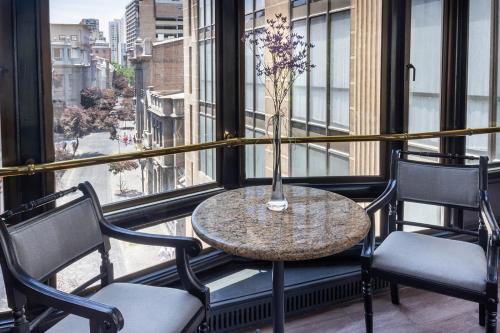 a table with chairs and a vase of flowers on a balcony at Hotel Fundador in Santiago