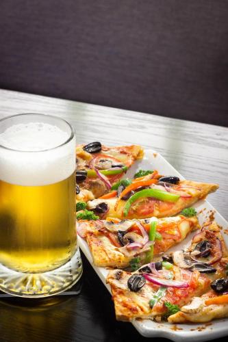 a plate of pizza and a glass of beer at Hotel Fundador in Santiago