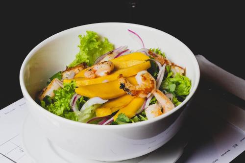 a white bowl of salad with shrimp and broccoli at Hotel Fundador in Santiago