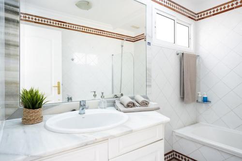 een witte badkamer met een wastafel, een bad en een spiegel bij EDEN RENTALS Fabulosas Vistas al Mar y Los Acantilados in Acantilado de los Gigantes