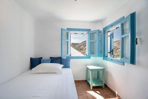 a bedroom with a bed and two windows at Kolimpithres beach house in Naousa