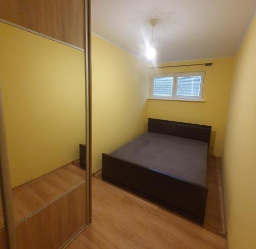 um pequeno quarto com uma cama e um espelho em Legionów Apartament em Konin