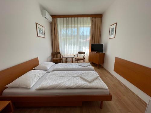 a bedroom with two beds and a television in it at Hello Balcsi Apartmanház in Tihany