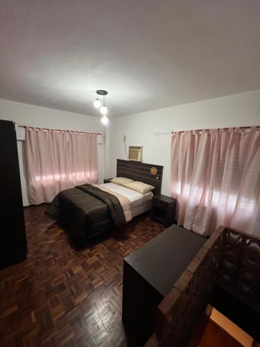 um quarto com uma cama, uma mesa e cortinas em El pasillo Centro em Rosário