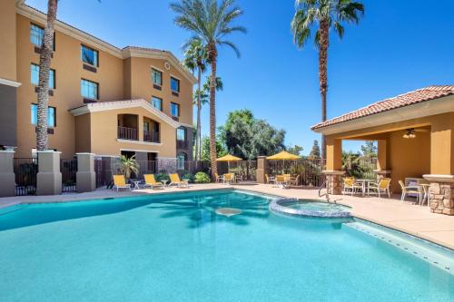 une piscine bordée de palmiers et un bâtiment dans l'établissement Holiday Inn Phoenix/Chandler, an IHG Hotel, à Chandler
