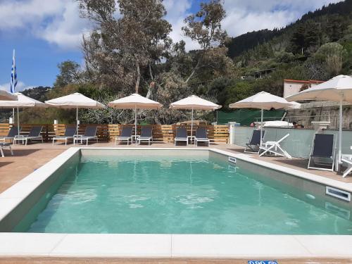 a swimming pool with chairs and umbrellas at Kostas Beach Apartments in Agios Gordios