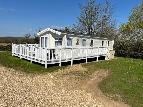 a white house with a large porch on a lawn at 3 Bedroom Caravan MC37, Shanklin, Isle of Wight in Shanklin