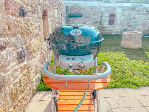 a grill sitting on a stand next to a wall at MINIQ HOMES 102 - Historical Stone House with Garden Cinema in Foca