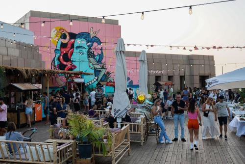 a crowd of people walking around a market with umbrellas at Seven Beach TLV - By 7even Hotels in Tel Aviv
