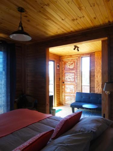 a bedroom with a bed and a blue couch at Cabañas & SPA Carilafquen in Laguna Verde