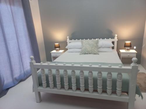 a bedroom with a white bed with two lamps at Kwikstertjie in Hermanus