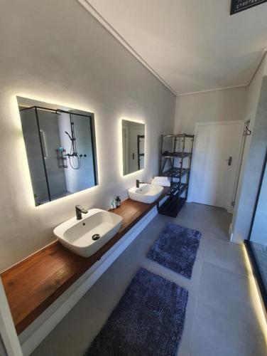 a bathroom with two sinks and two mirrors at Kwikstertjie in Hermanus