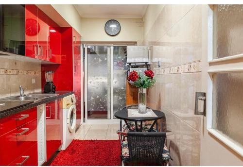 une cuisine avec des placards rouges et une table avec un vase de fleurs dans l'établissement Cantinho da Lena, à Sacavém