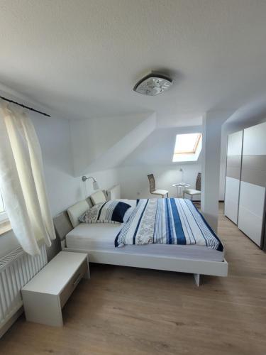 a white bedroom with a bed and a table at Pension Schützenhaus Leisnig in Leisnig
