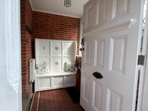 een hal met een witte deur en een bakstenen muur bij Forest Side Guesthouse in Lyndhurst