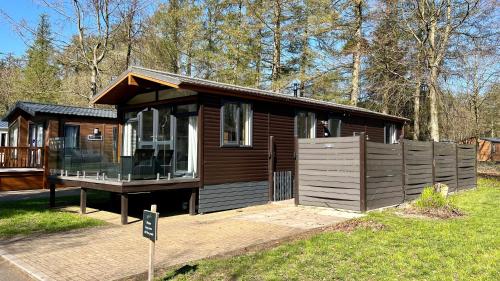 uma pequena cabana de madeira com um alpendre na relva em Barnston Lodge em Newton on the Moor