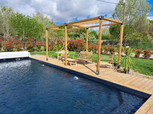 une terrasse en bois avec bancs à côté d'une piscine dans l'établissement Studio en campagne, à Avignon