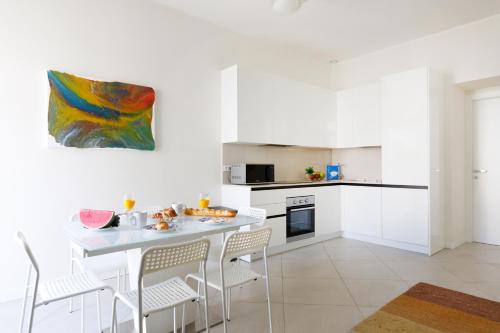 une cuisine blanche avec une table et des chaises dans l'établissement Gazagnaire YourHostHelper, à Cannes