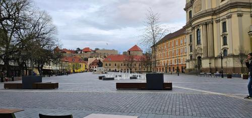 a city square with benches and buildings in a city at Belvárosi apartman in Eger