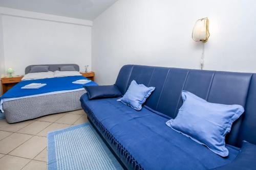ein blaues Sofa in einem Zimmer mit einem Bett in der Unterkunft Apartments Sopic in Rogoznica