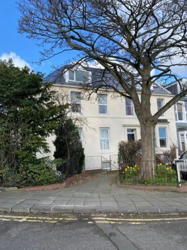 a white house with a tree in front of it at Moor View Apartment, near city centre and stadium in Town Moor