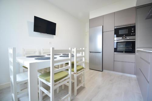 a kitchen with a table and chairs and a refrigerator at Apartamento en pleno centro de Portonovo, Sanxenxo in Sanxenxo