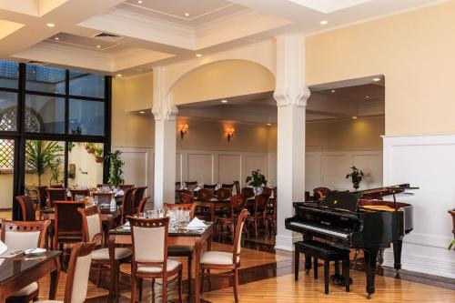 un piano de cola en un restaurante con mesas y sillas en Marques Plaza Hotel, en Pouso Alegre