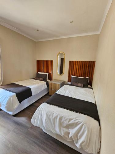 a bedroom with two beds and a mirror at Pine View Guesthouse Graskop in Graskop