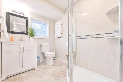 a white bathroom with a shower and a toilet at 653 3rd St unit1 AfterDune Delight 2BR Near Beach in Somers Point