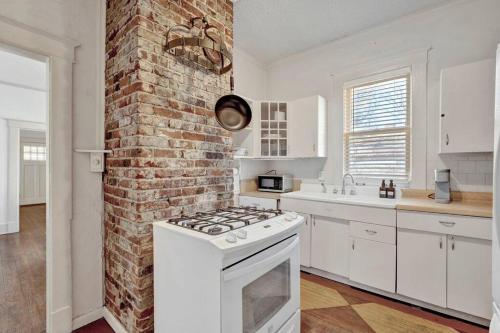uma cozinha com uma parede de tijolos e um fogão forno superior em Charming cottage near Memphis zoo and restaurants em Memphis