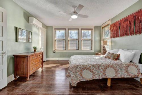 um quarto com uma cama, uma cómoda e janelas em Charming cottage near Memphis zoo and restaurants em Memphis