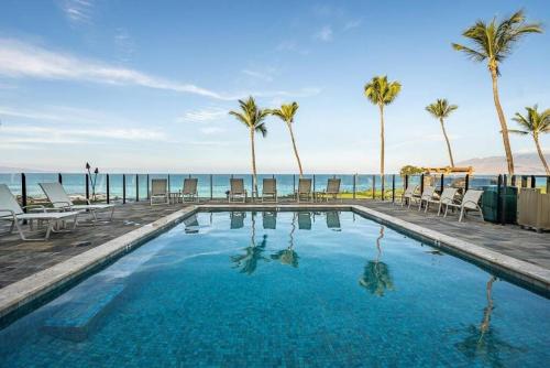 a swimming pool with palm trees and the ocean at Enjoy Your Oceanside Dream at Kihei Surfside in Wailea