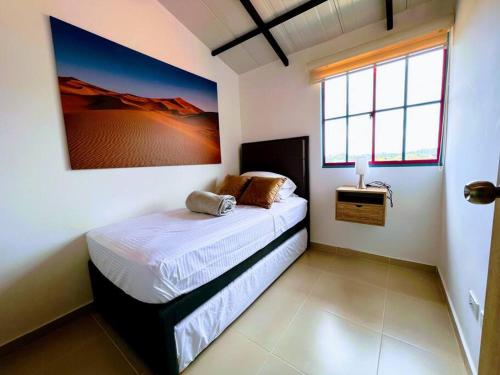 a bedroom with a bed with a picture on the wall at Apto Nuevo, Tranquilo, Bonito, 5 min Plaza Principal in Guatapé