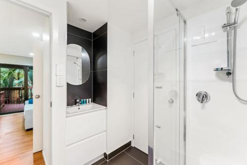 a white bathroom with a sink and a shower at A 1BR slice of Titirangi Heaven - WiFi - Netflix in Auckland