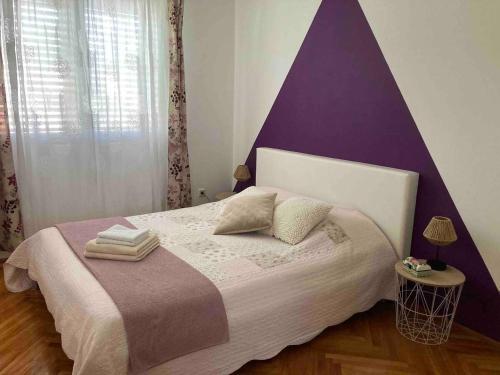 1 dormitorio con 1 cama grande y cabecero púrpura en Family Apartment Bella en Dubrovnik