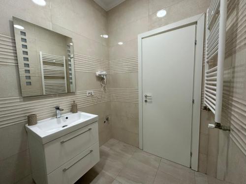 Un baño blanco con lavabo y espejo. en Golden Garden Luxury Apartment in Bucharest, en Bucarest
