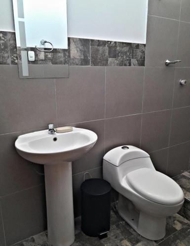a bathroom with a sink and a toilet and a mirror at La Ruta in Paracas