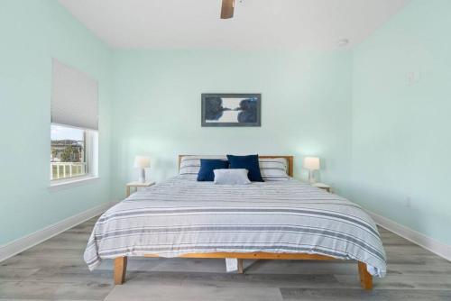 a white bedroom with a large bed with blue pillows at Walk to downtown seafood market Bay views in Pensacola