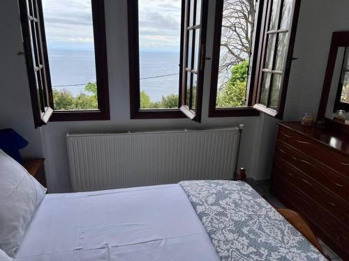 a bedroom with a bed and two windows with a view at Sea & Mountain Pelion in Mouresi