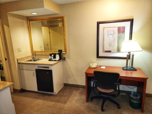 a hotel room with a desk and a sink at La Quinta by Wyndham Appleton College Avenue in Appleton