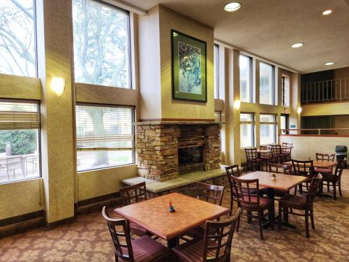 a restaurant with tables and chairs and a fireplace at La Quinta by Wyndham Appleton College Avenue in Appleton