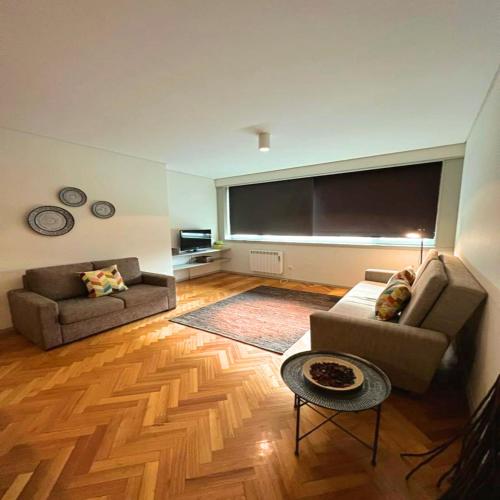 a living room with two couches and a large screen at bnapartments Trindade in Porto