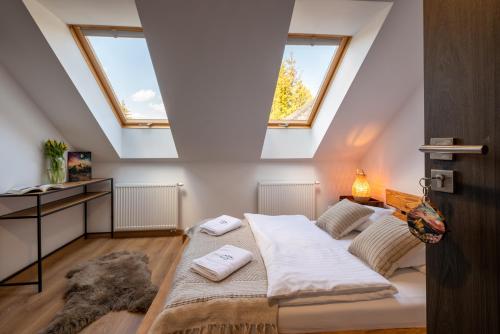 a attic bedroom with a bed and two windows at Centrum Bieszczad in Lutowiska