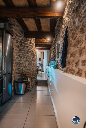 une cuisine avec un mur en pierre et un comptoir avec un réfrigérateur dans l'établissement Maison de village atypique à 5min du Pont du Gard, à Vers-Pont-du-Gard