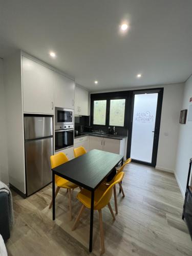 a kitchen with a black table and yellow chairs at Casa da Margarida in Vila Nova de Foz Coa