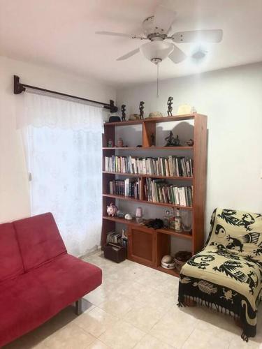 a living room with a red chair and a book shelf at Isla Mujeres departamento, hasta para 6 personas. in Isla Mujeres