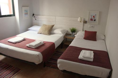twee bedden in een hotelkamer met handdoeken erop bij Pensión Nochela Sevilla in Sevilla