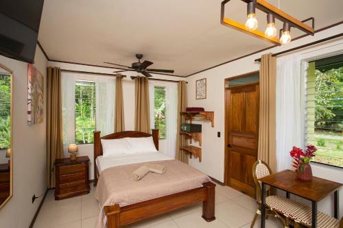 a bedroom with a bed and a table and windows at Manzanillo Caribbean Resort in Puerto Viejo