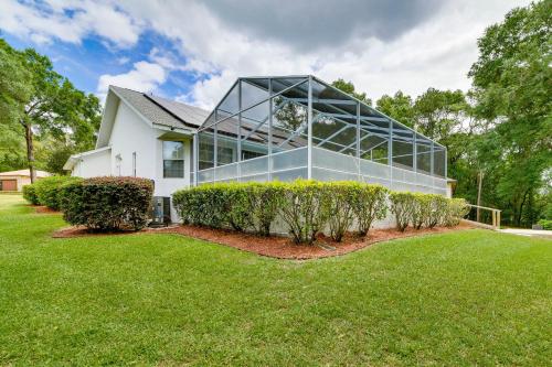a glass house with a lawn in front of it at Lanai and Grill Sunny Home Near Rainbow Springs! in Dunnellon