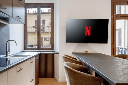 a kitchen with a tv with a n on the wall at Bilocale Moderno - City Center in Milan